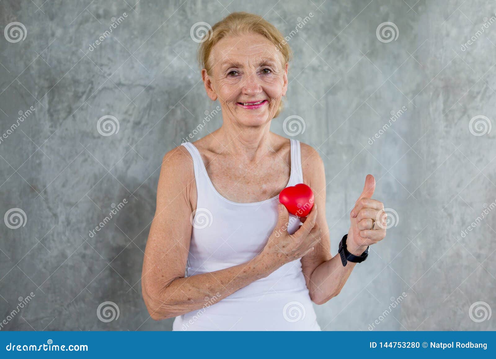 Senior Woman Holding Red Heart Toy And Show Thumbs