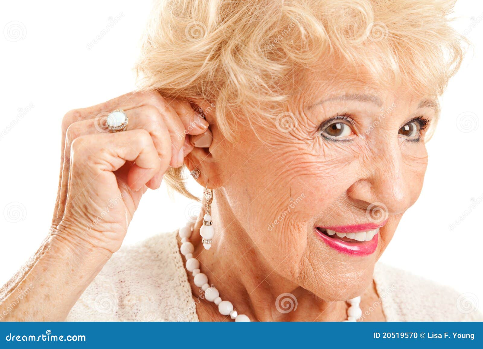 senior woman inserts hearing aid