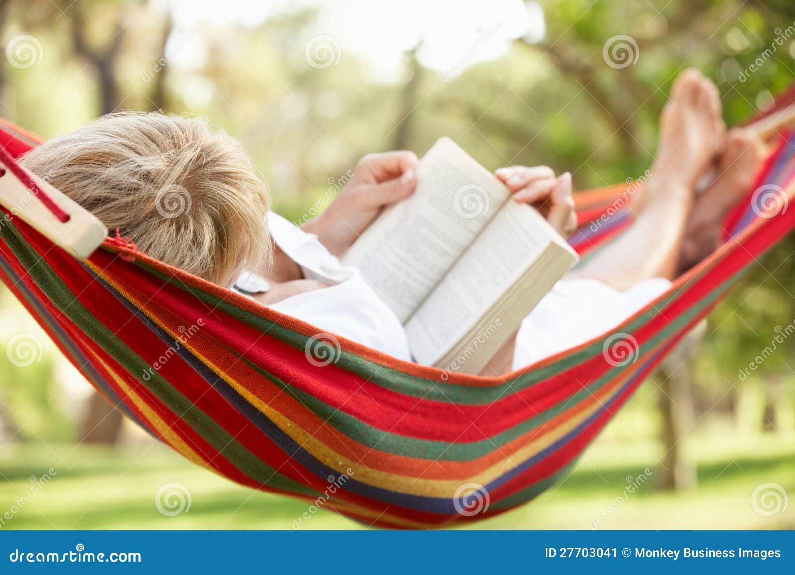 senior woman relaxing in hammock with book
