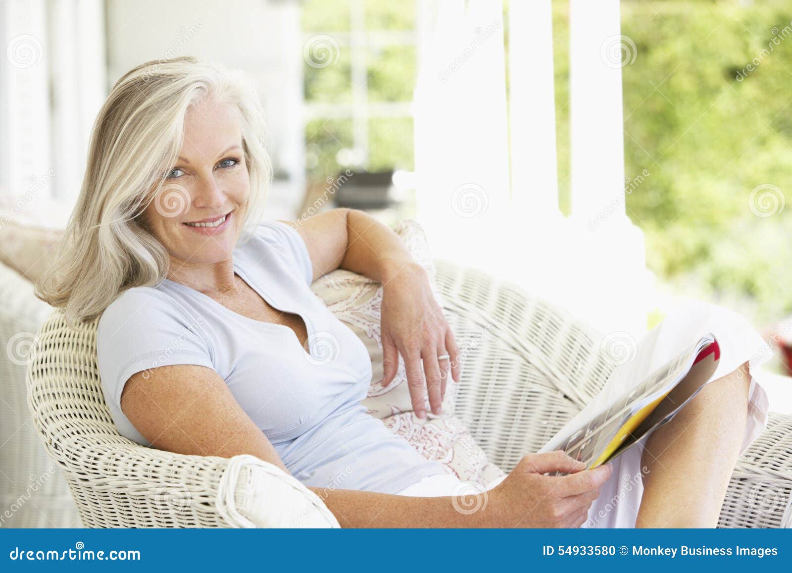 senior woman sitting outside reading magazine