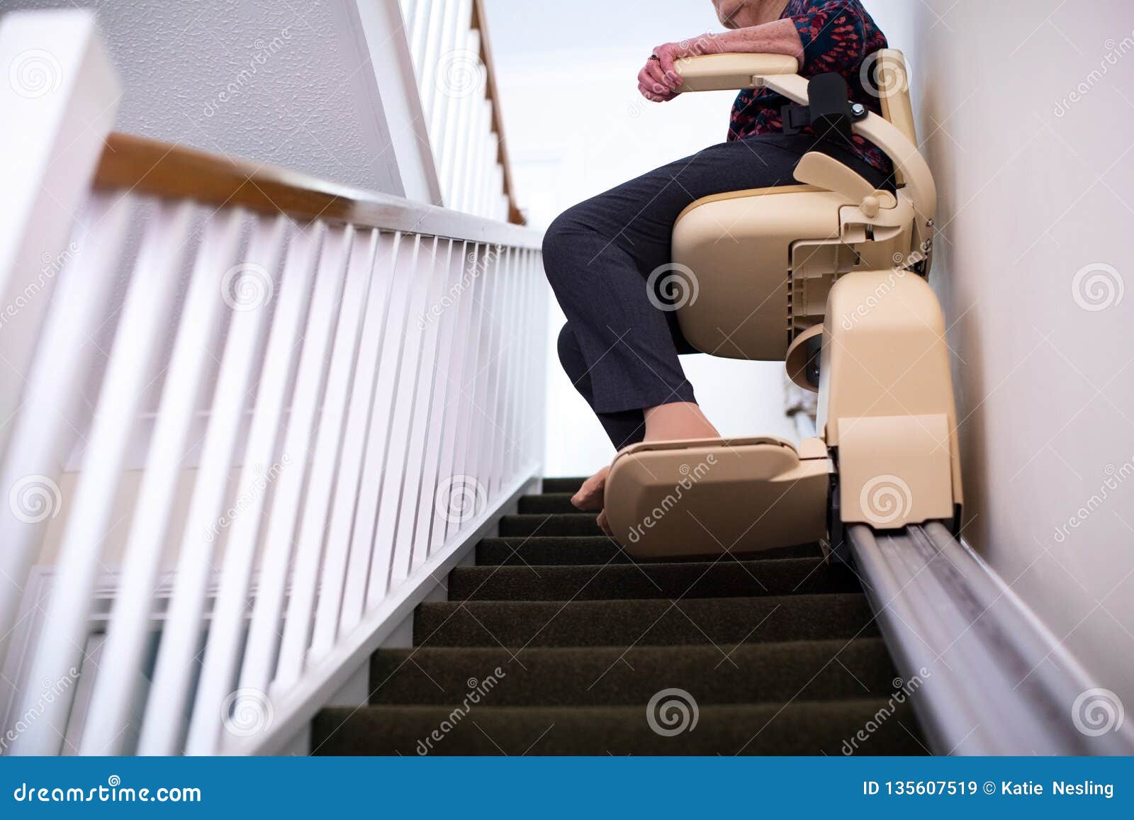 detail of senior woman sitting on stair lift at home to help mobility