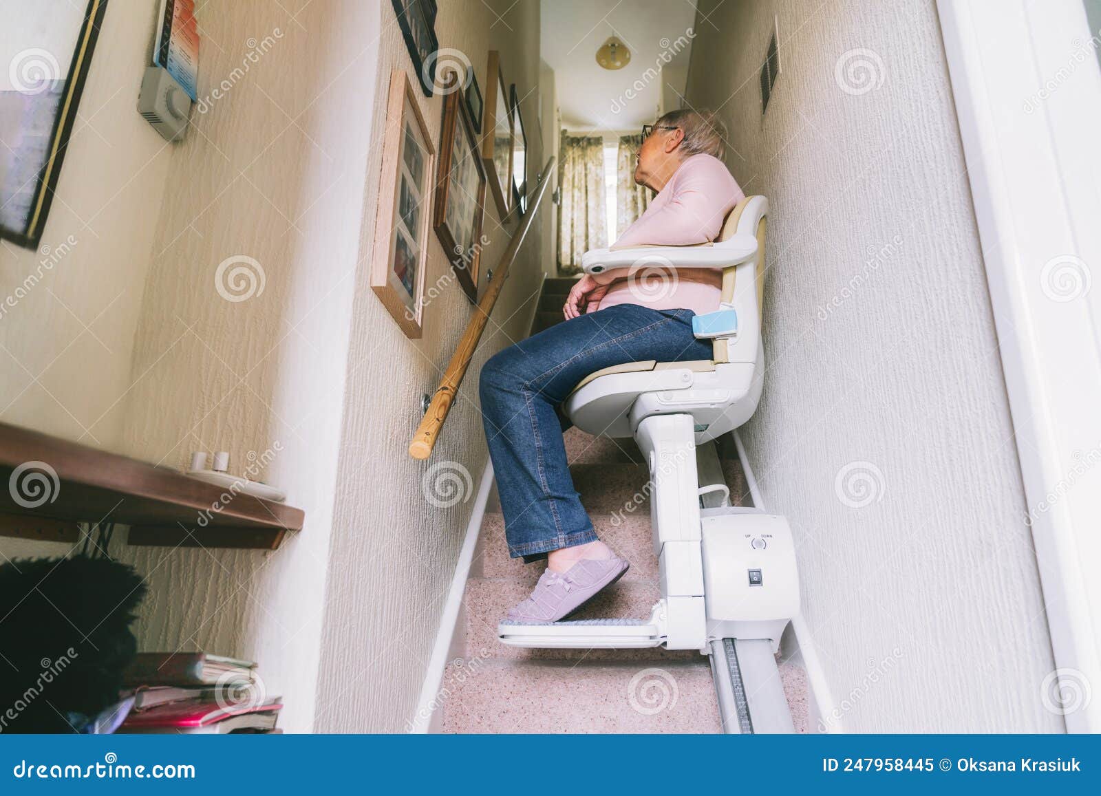 senior woman using automatic stair lift on a staircase at her home. medical stairlift for disabled people and elderly