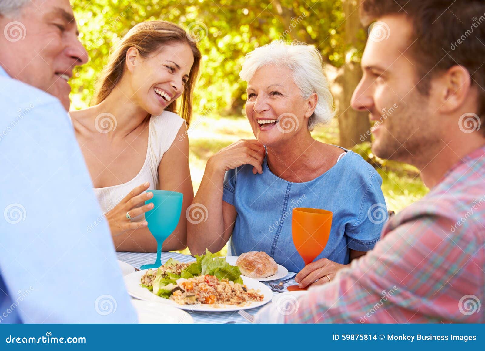 a senior and a young adult couple eating together outdoors