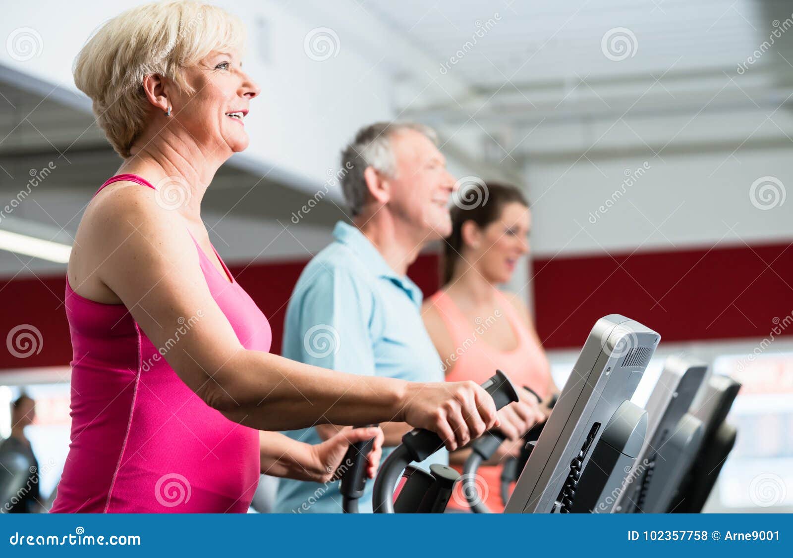 Seniors Training on Cross Trainer with Personal Trainer at the G Stock Photo Image of club