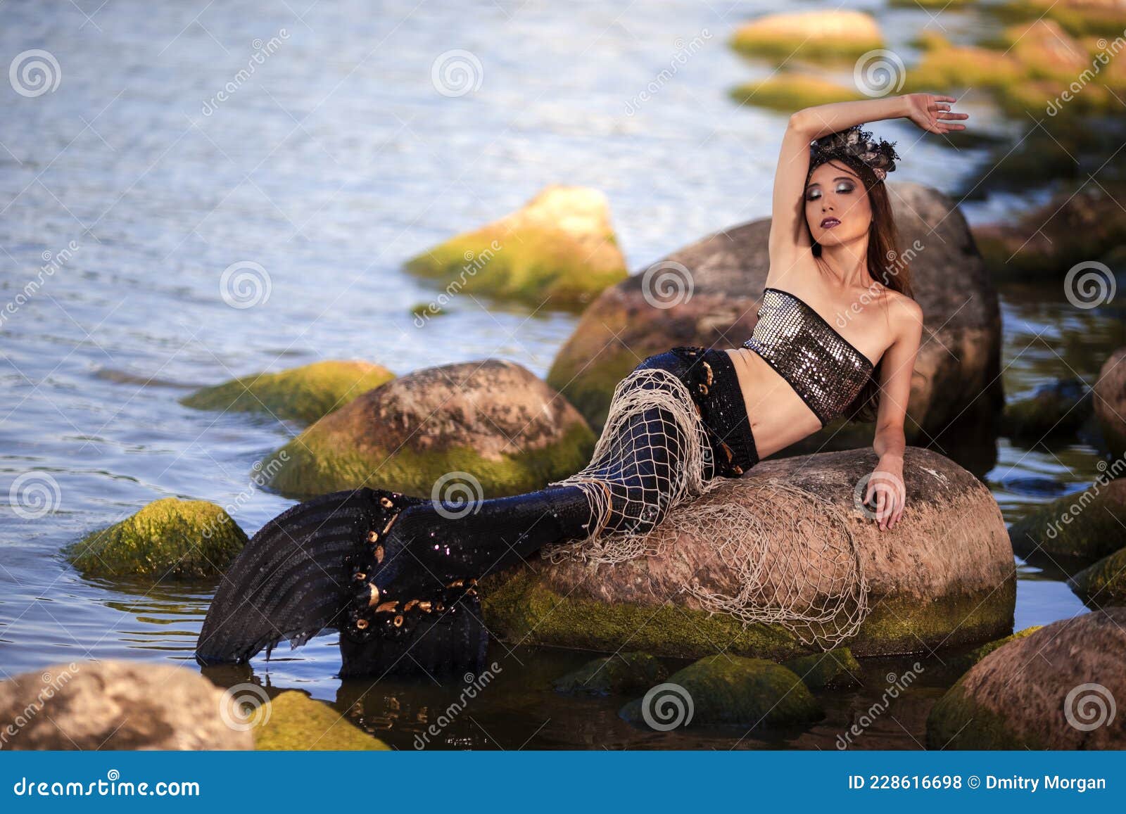 Sensual Mermaid with Net at Rocky Sea Coast Wearing Seashell