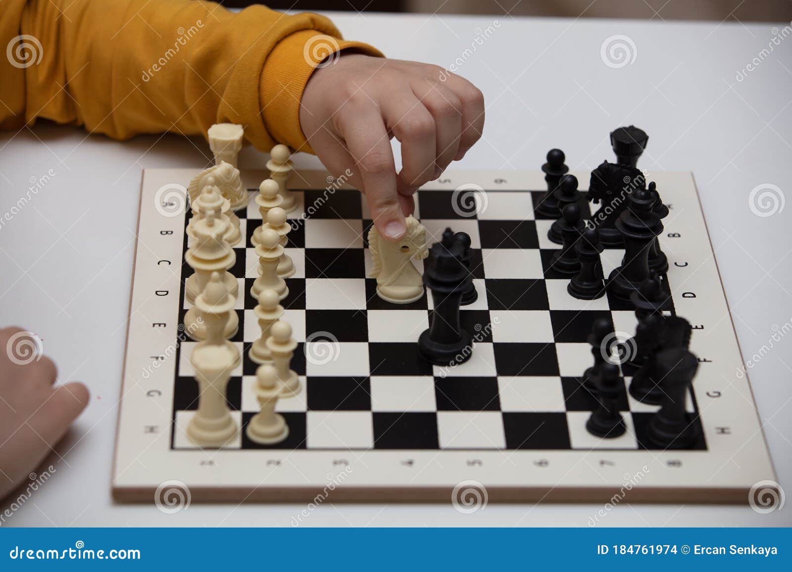 Senta-se à mesa e joga xadrez a criança concentra-se no jogo
