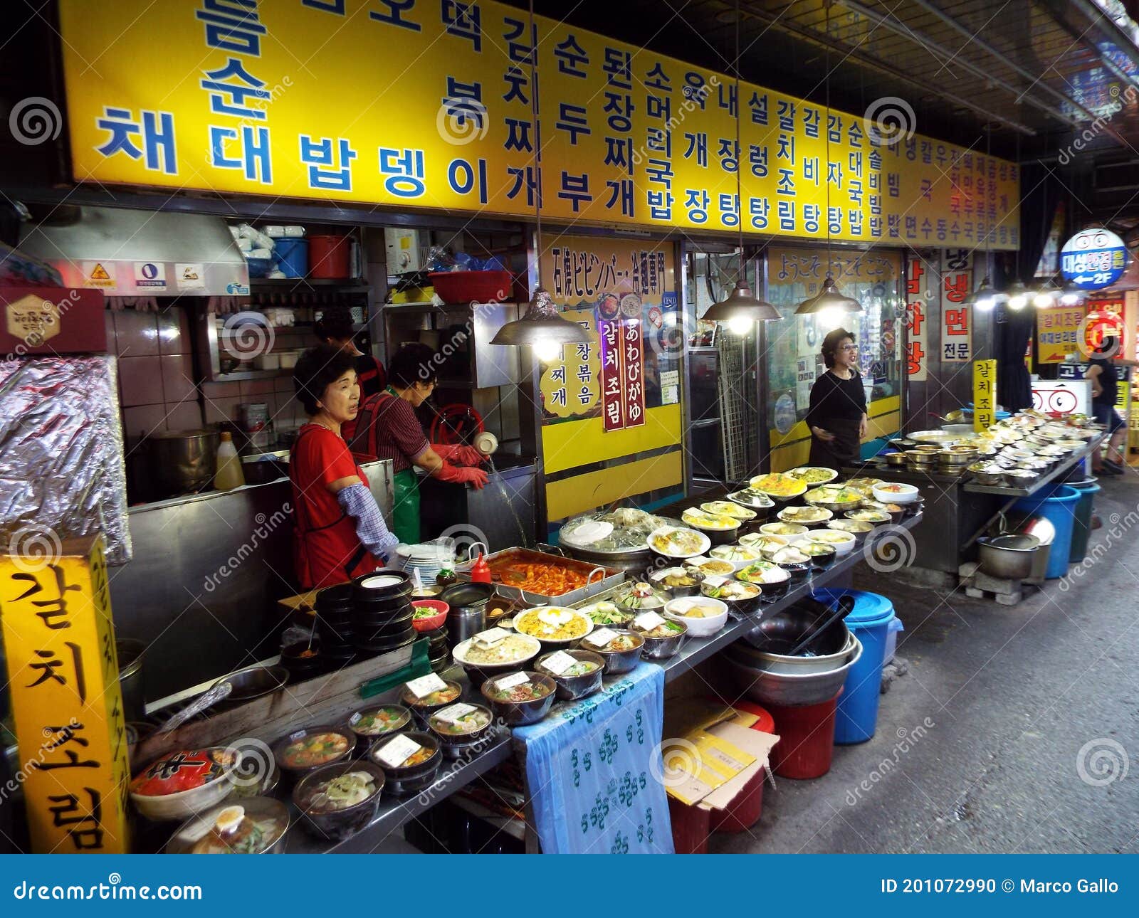 Three Women at a Food Stall in a Street of the Namdaemun Market. Seoul