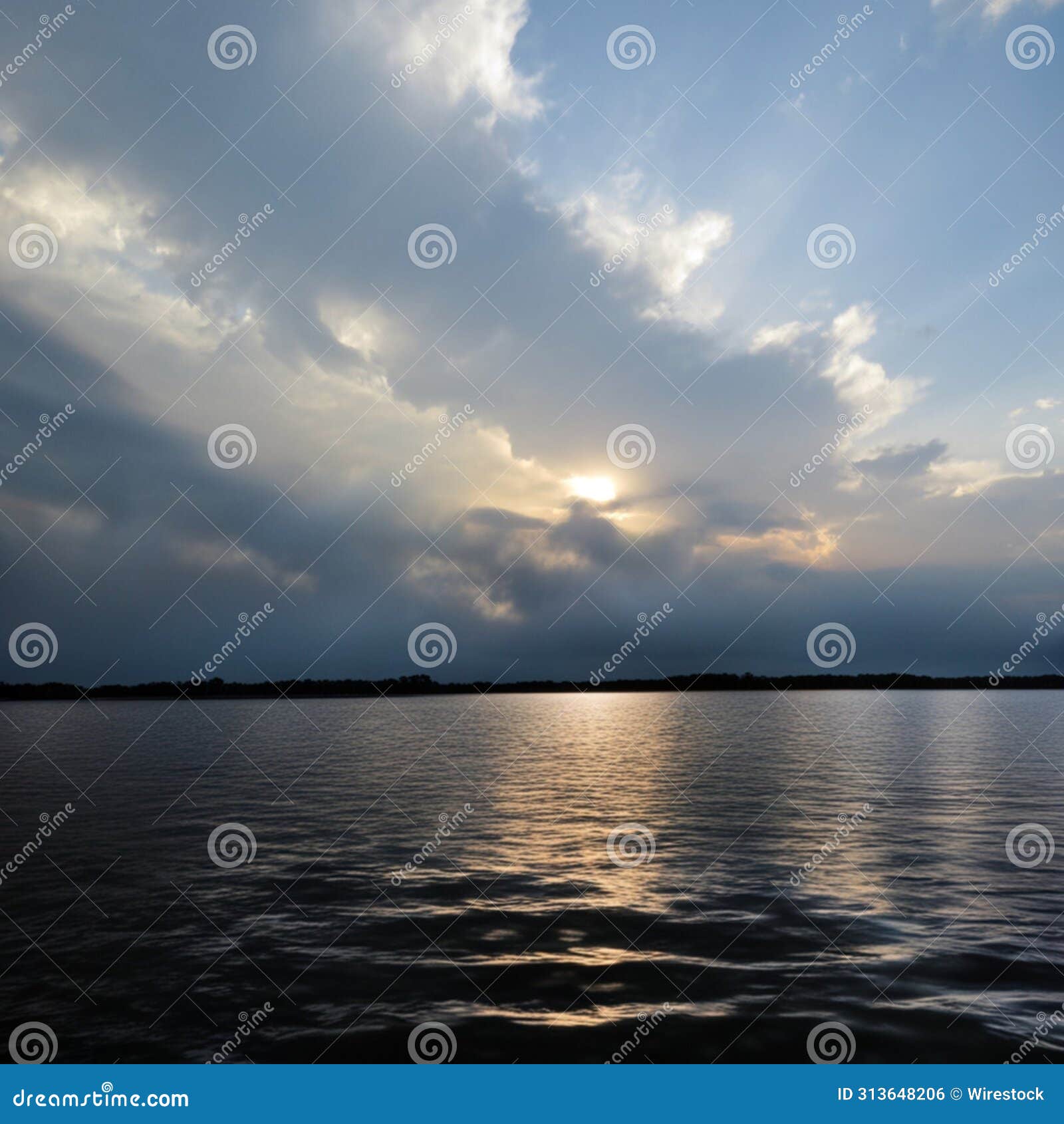 serene lake under a cloudy sky with sunbeams. lake conroe, texas