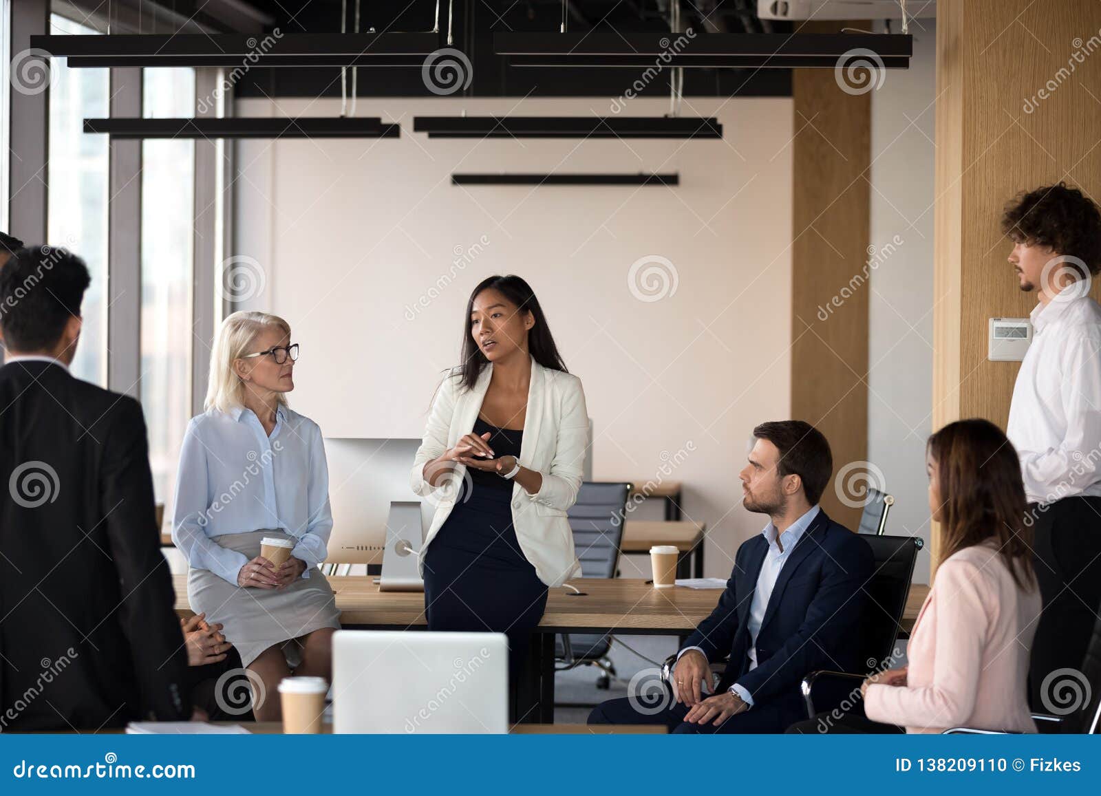 serious asian coach speaking at diverse corporate group meeting