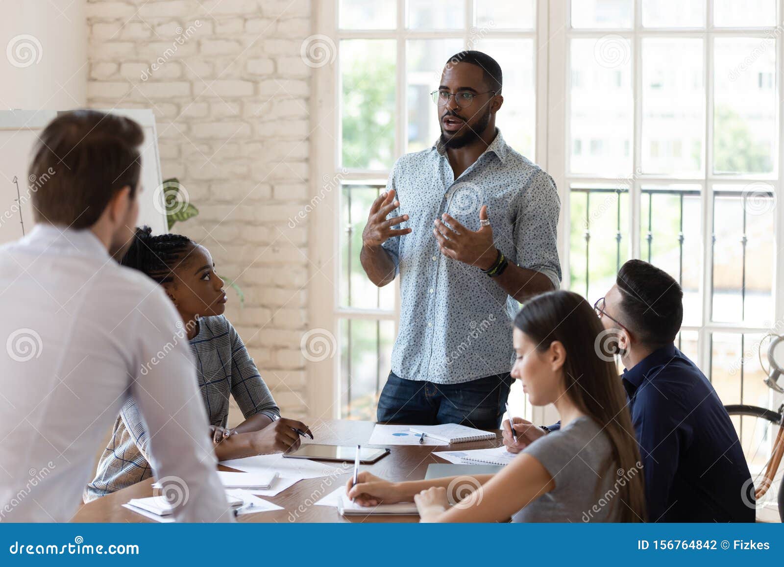 serious black manager talk to diverse staff people at meeting