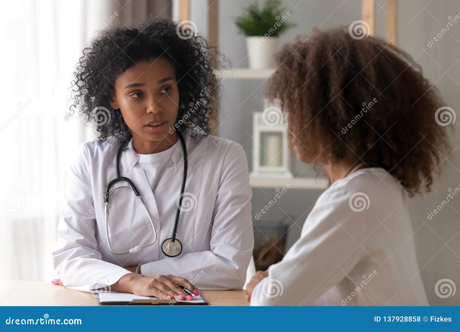 serious black female doctor consult teenage girl