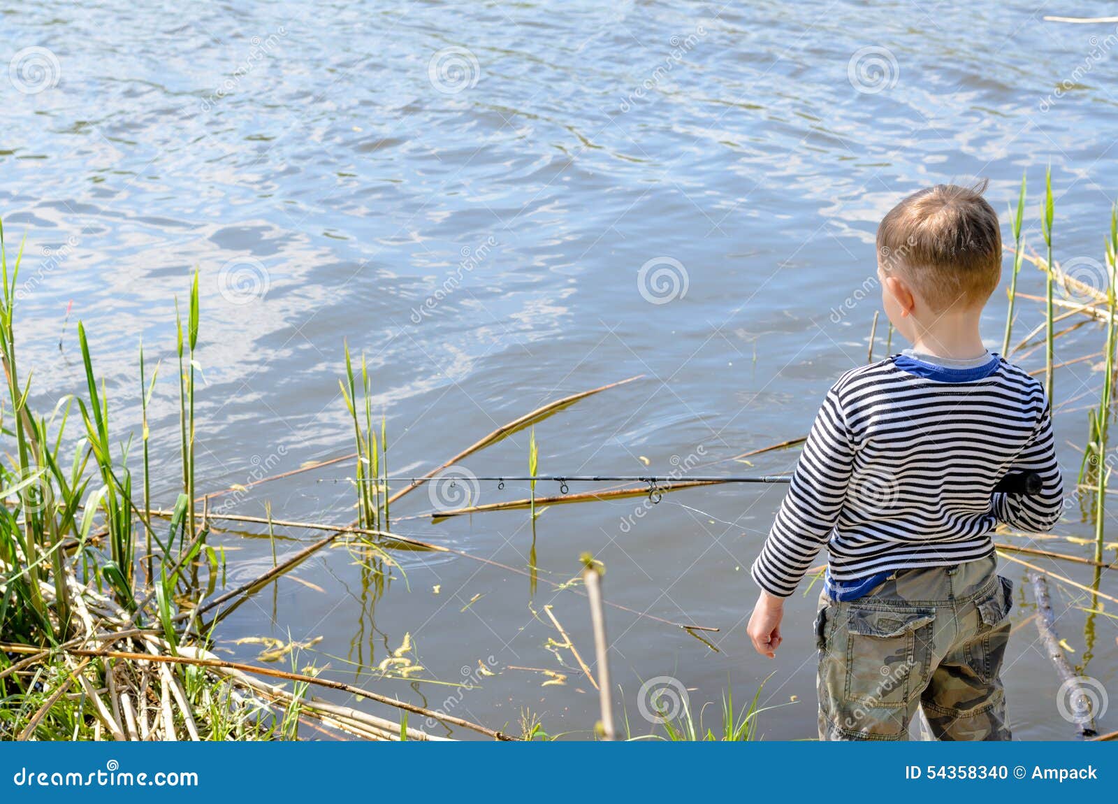 Serious Boy Sitting on Riverside while Fishing Stock Photo - Image