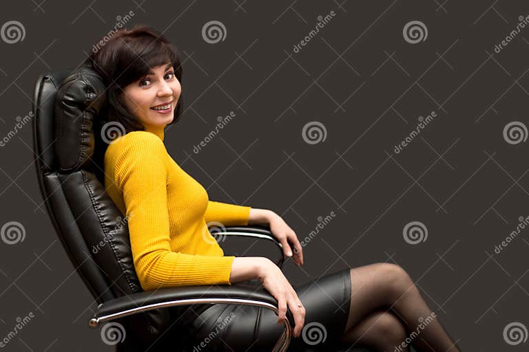 A Serious Woman in a Bright Yellow Blouse is Sitting Leather