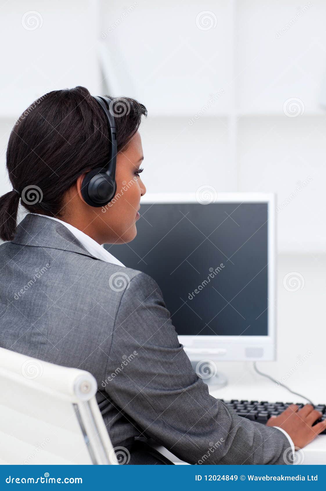 Serious businesswoman working at a computer with headset on in a call center