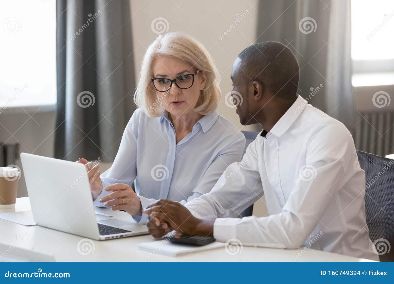 serious busy aged mentor helping to new african employee