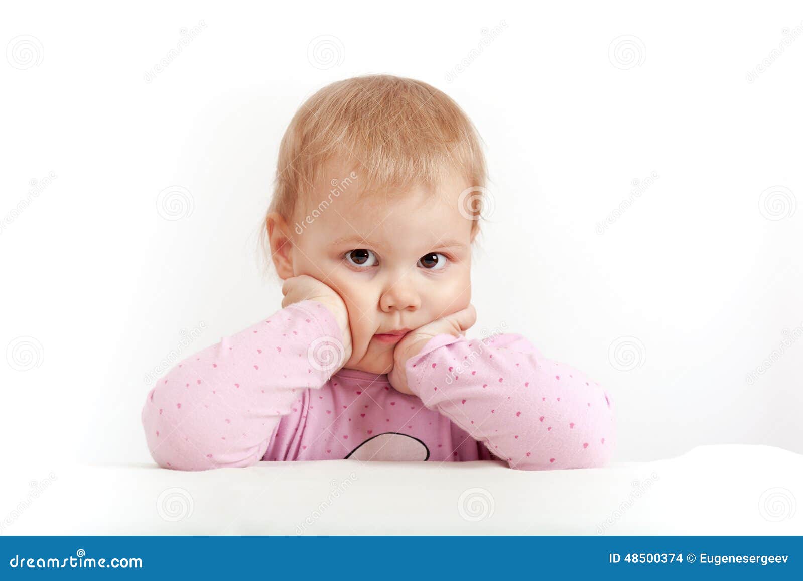 Serious Caucasian baby girl in pink on white background, closeup studio portrait