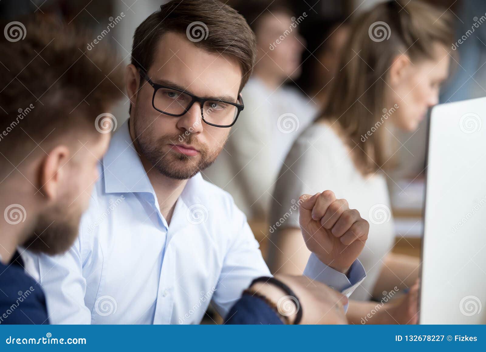 serious focused male employee listening to colleague