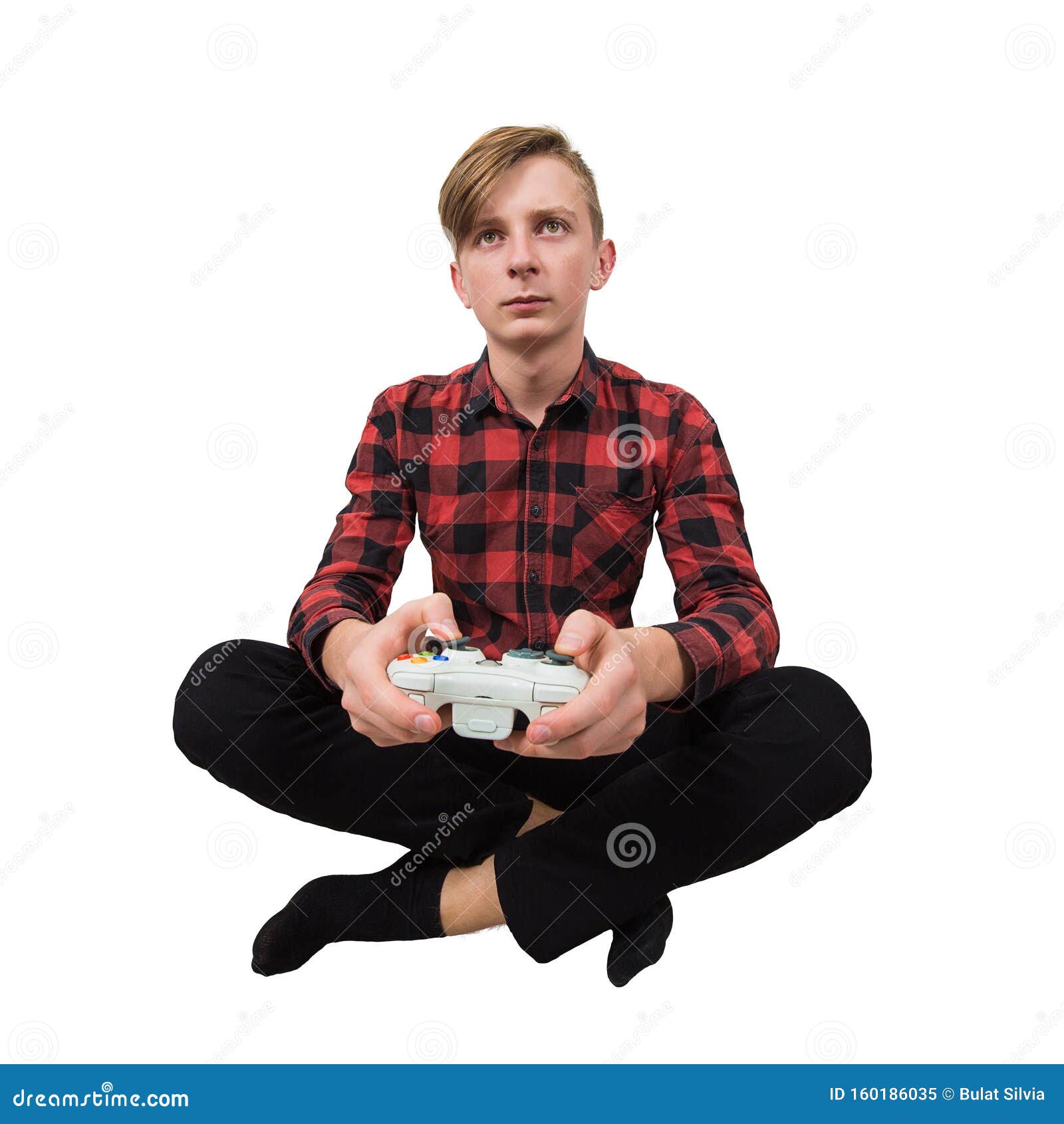 serious intent teen guy seated on the floor playing video games  over white background. boy stand all ears holding