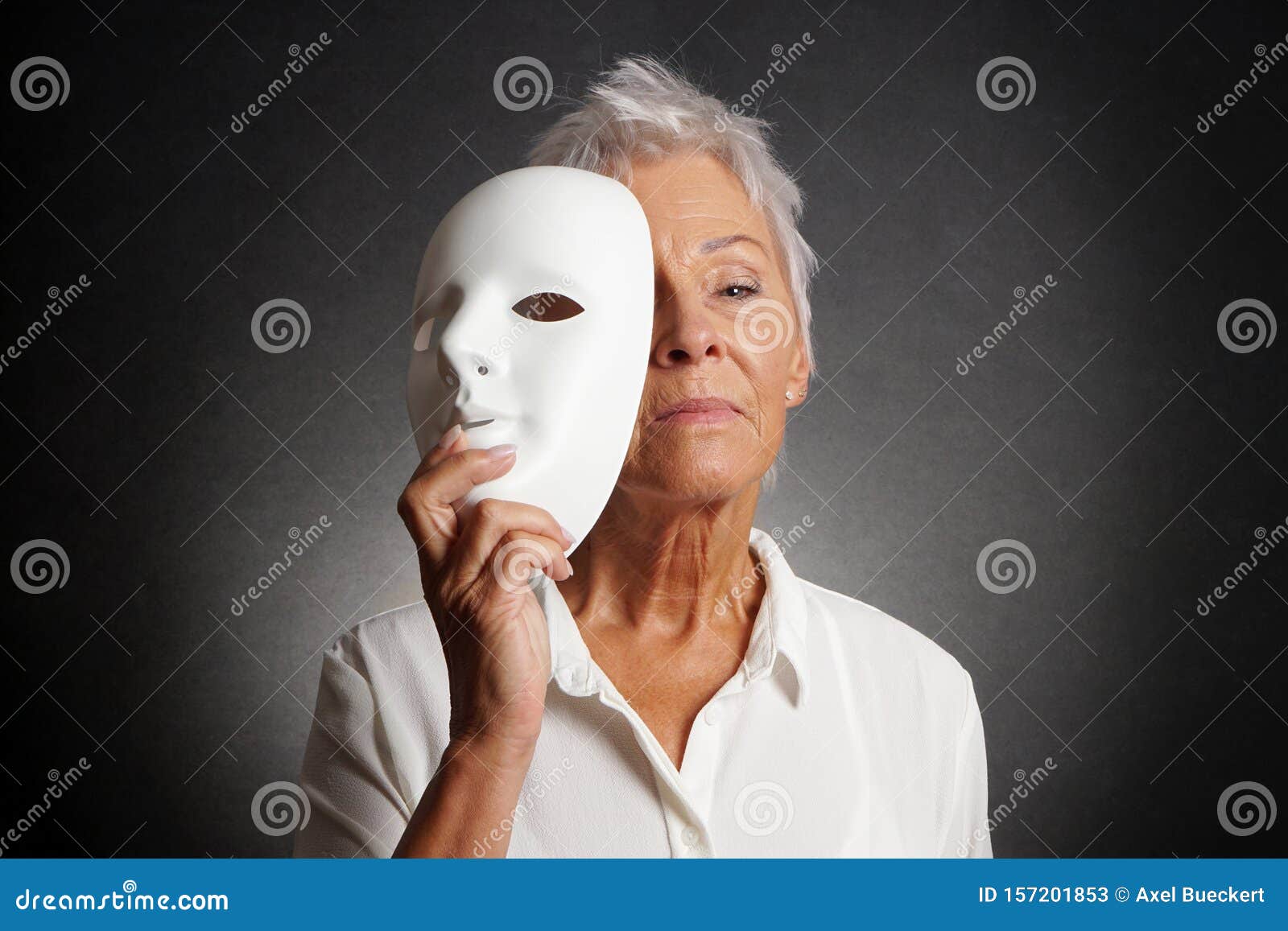 serious older woman revealing face behind mask