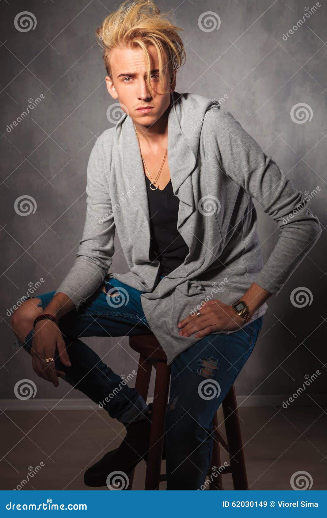 serious male model wearing rugged jeans sitting chair i portrait studio looking camera 62030149