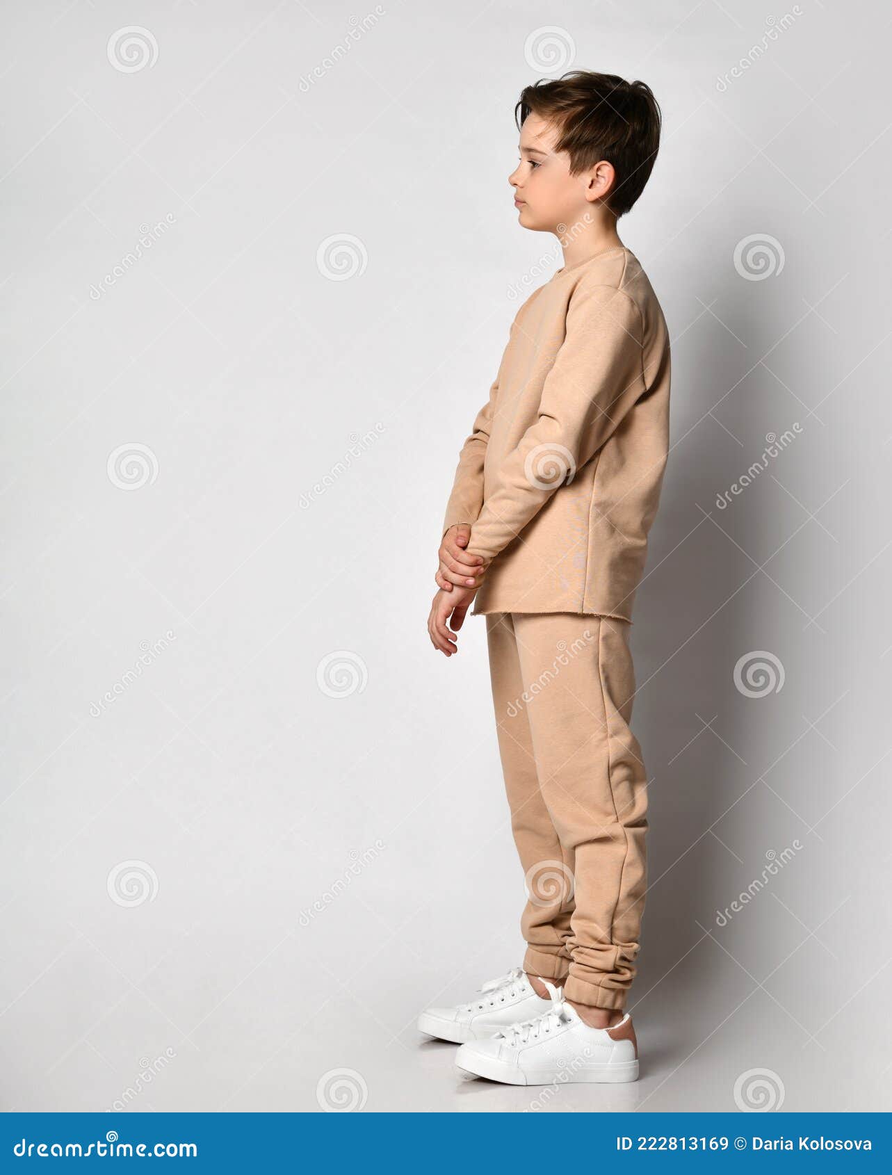 serious preteen boy child standing sideway looking forward over studio wall