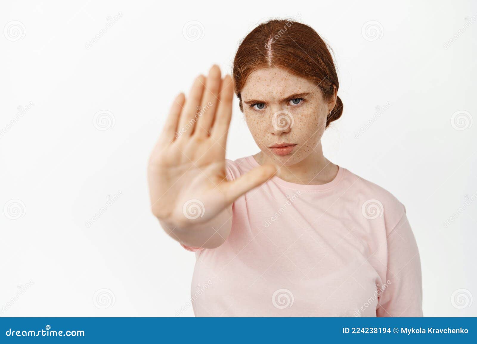 serious redhead woman extend her hand to stop, saying no, furrow eyebrows determined to prohibit, forbid smth bad