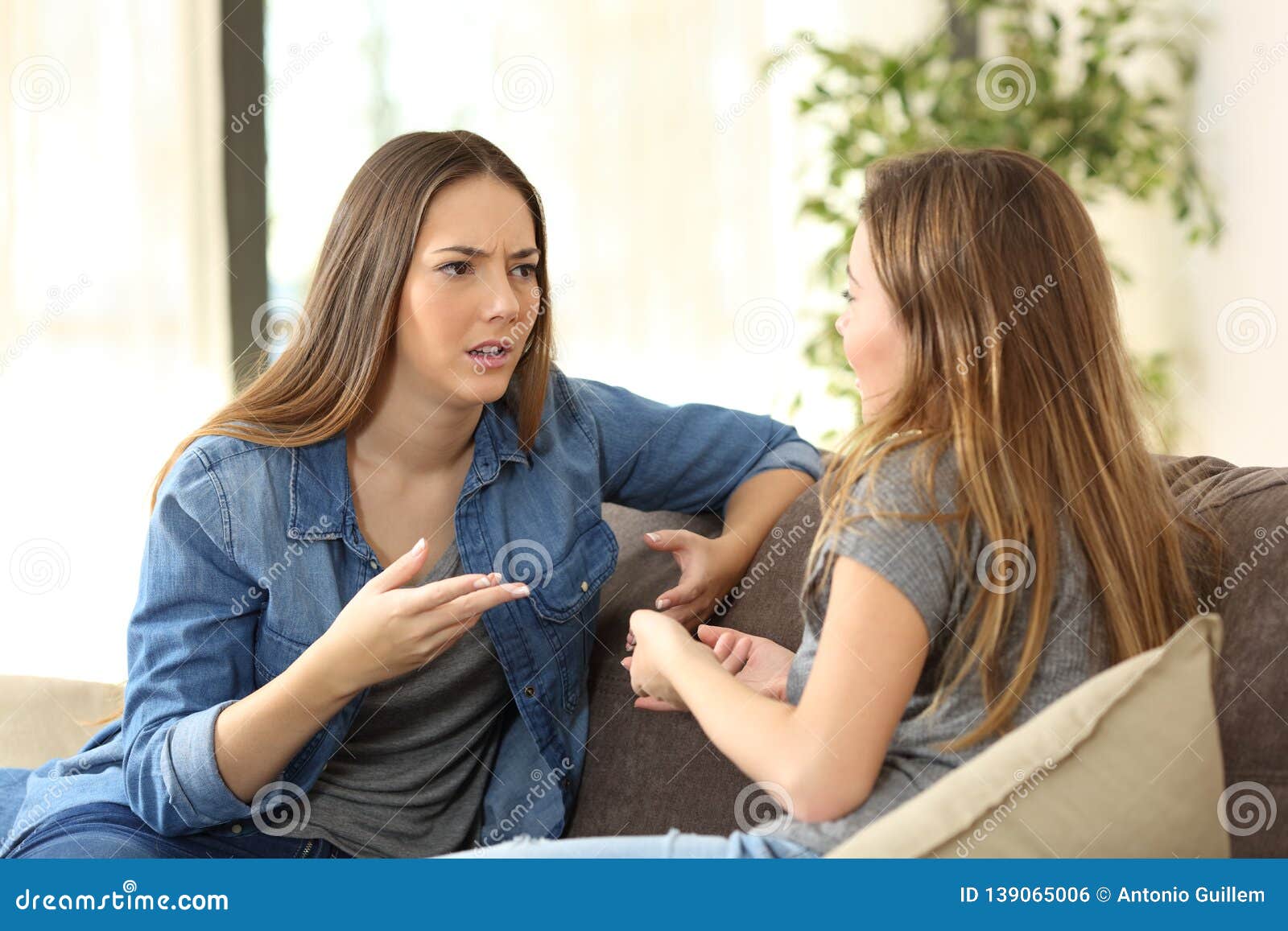 serious women talking on a couch at home