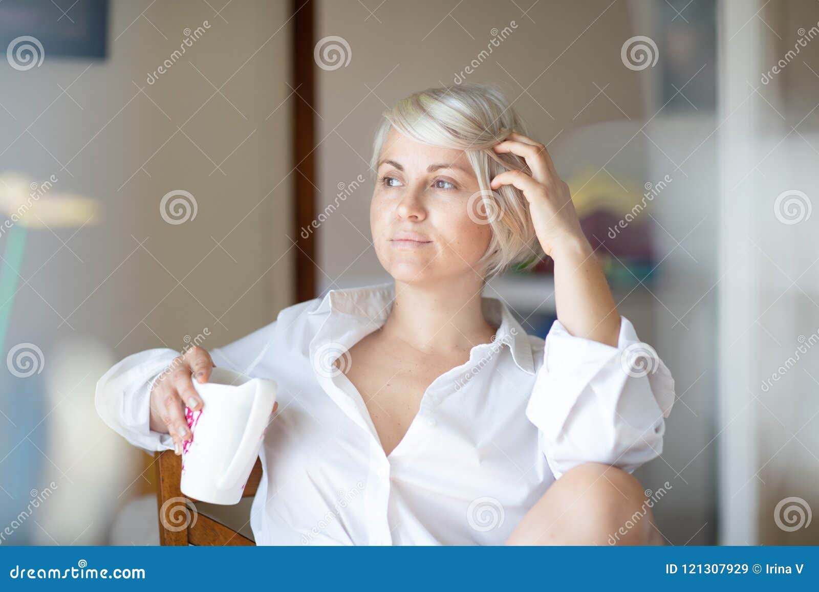 Serious Young Blonde Woman Sitting In Her Room Looking Pensively In The ... Open Window At Morning
