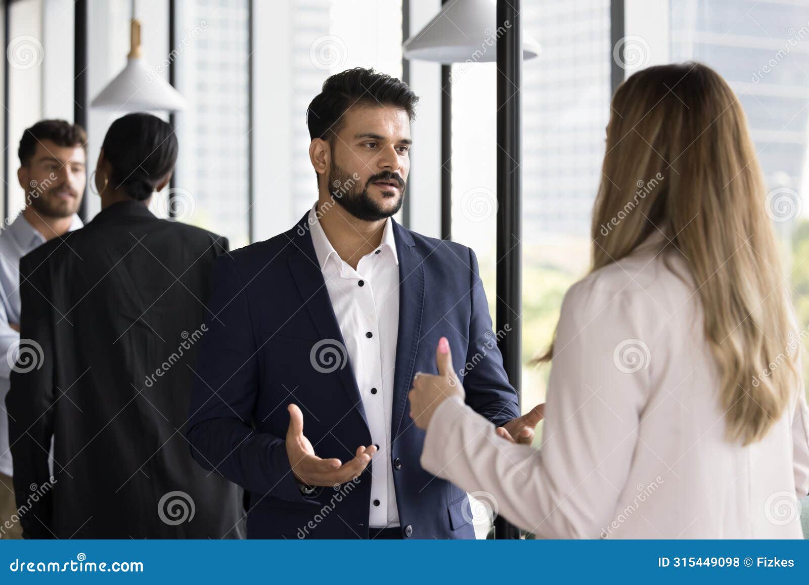 serious young indian businessman talking to caucasian female colleague
