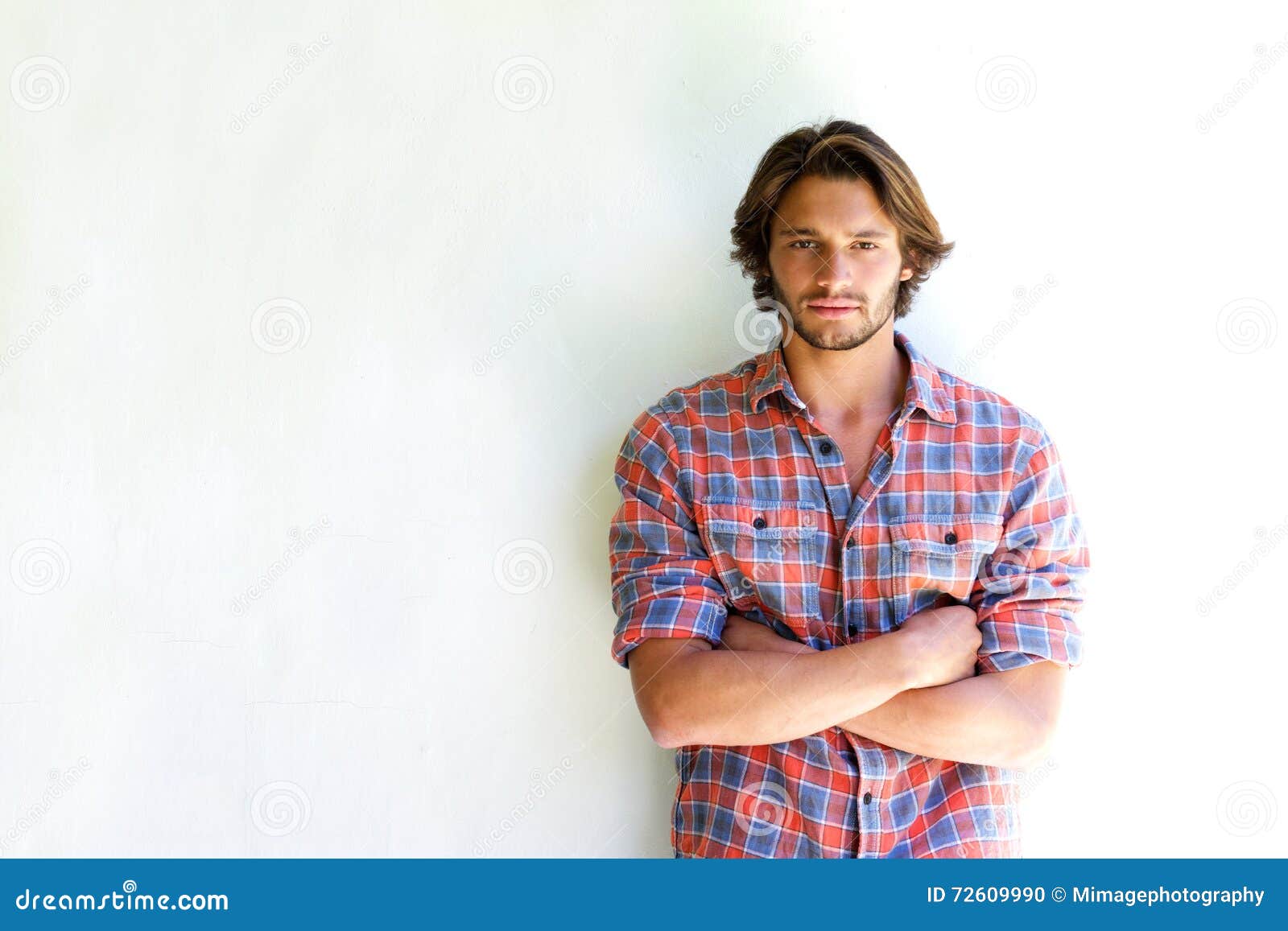 serious young man with arms crossed on white background