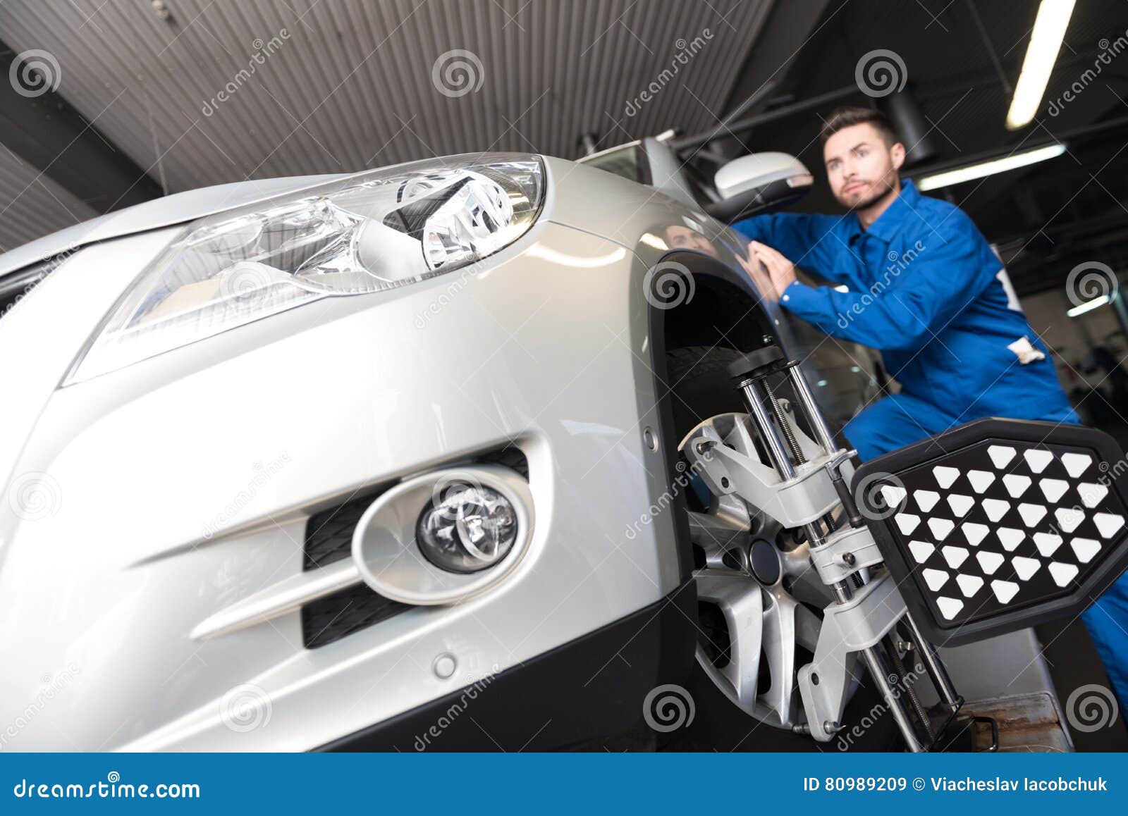 Serious Young Mechanic Adjusting Automobile Wheel Alignment Stock Image