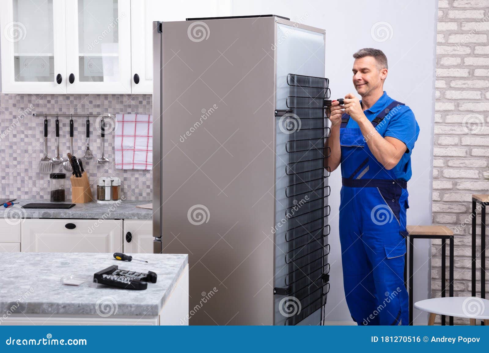 serviceman in overall working on fridge