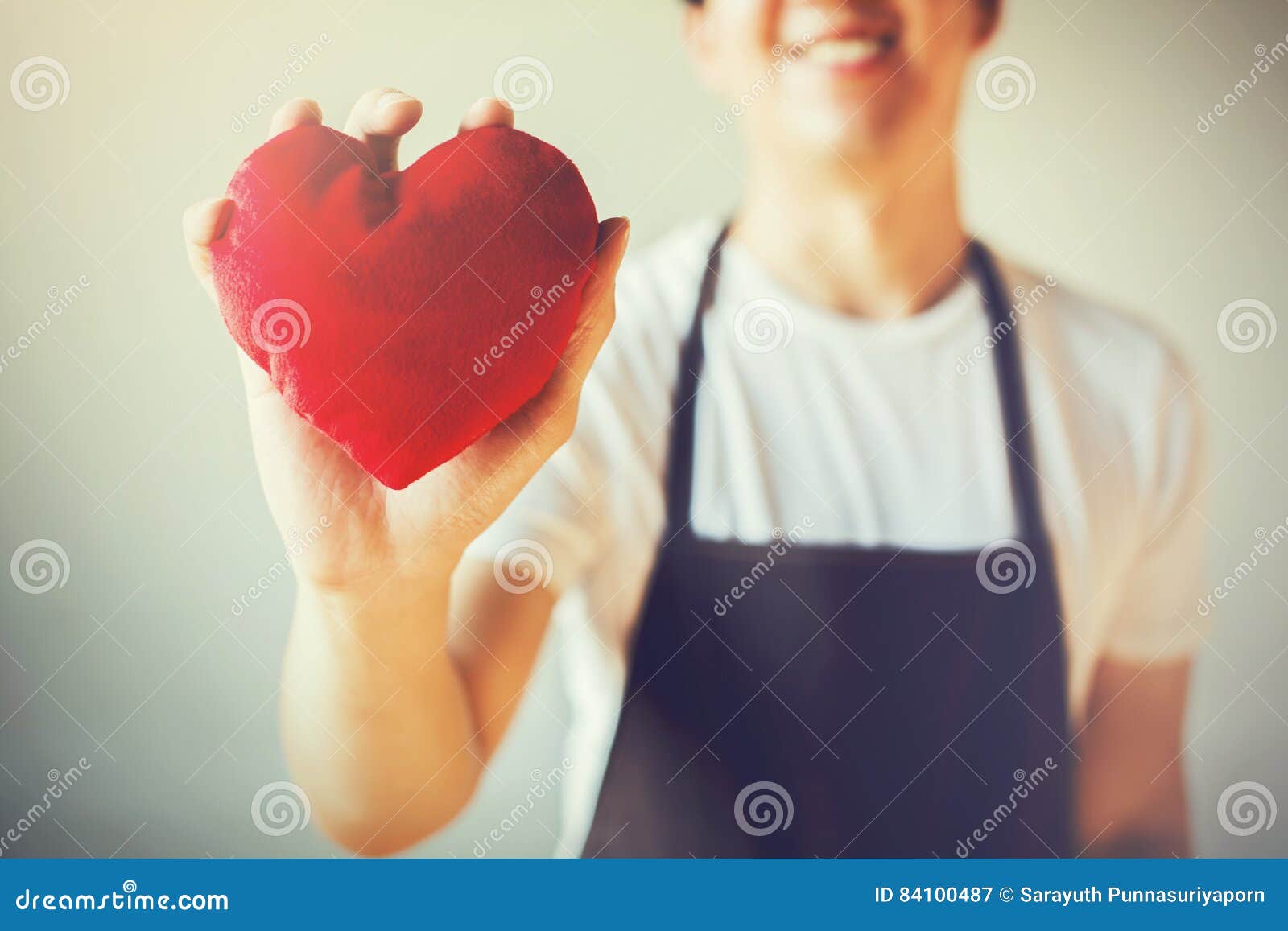 servicing man in apron holding heart - customer relationship and service minded business concept