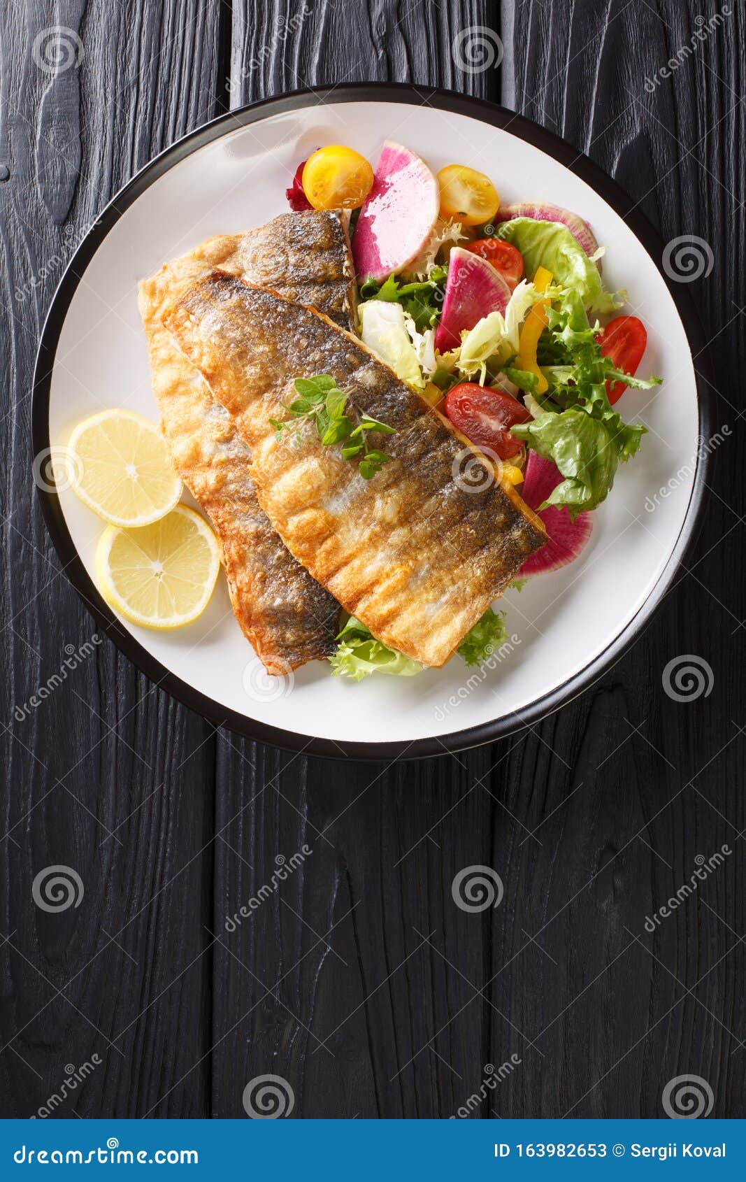 Serving Fried Sea Bass Fillet with Fresh Vegetable Salad and Lemon ...