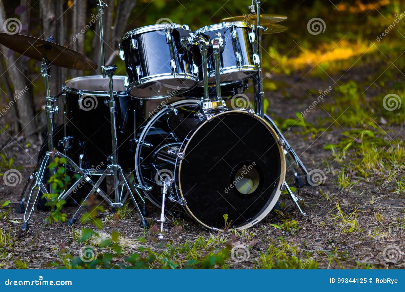 Set of Black Battery Drum Set Under the Tree on the Grass Stock Image