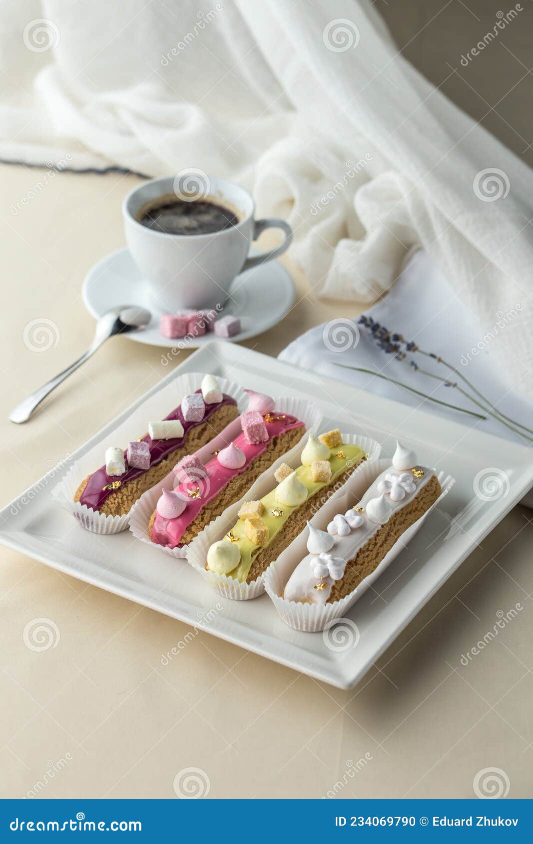 set of french dessert eclairs with colorfulicing and cup of coffee on the table