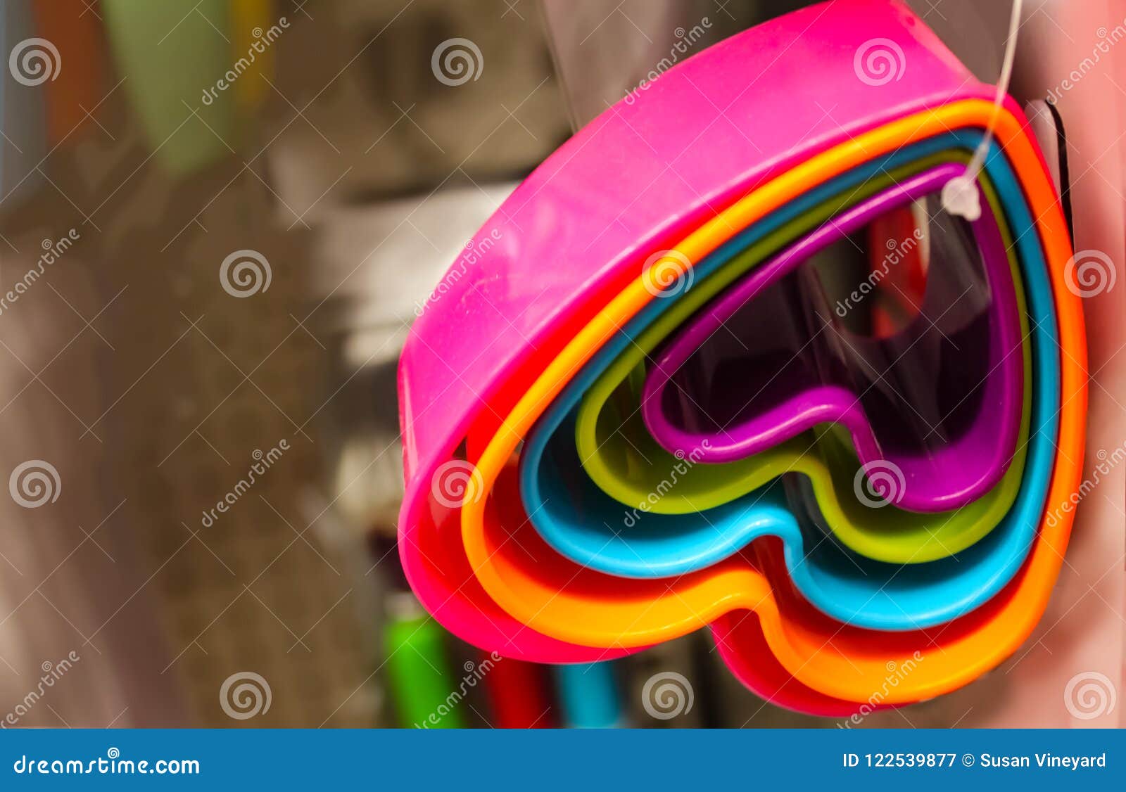 set of heart-d brightly colored cookie cutters hanging from a plastic tie against blurred background