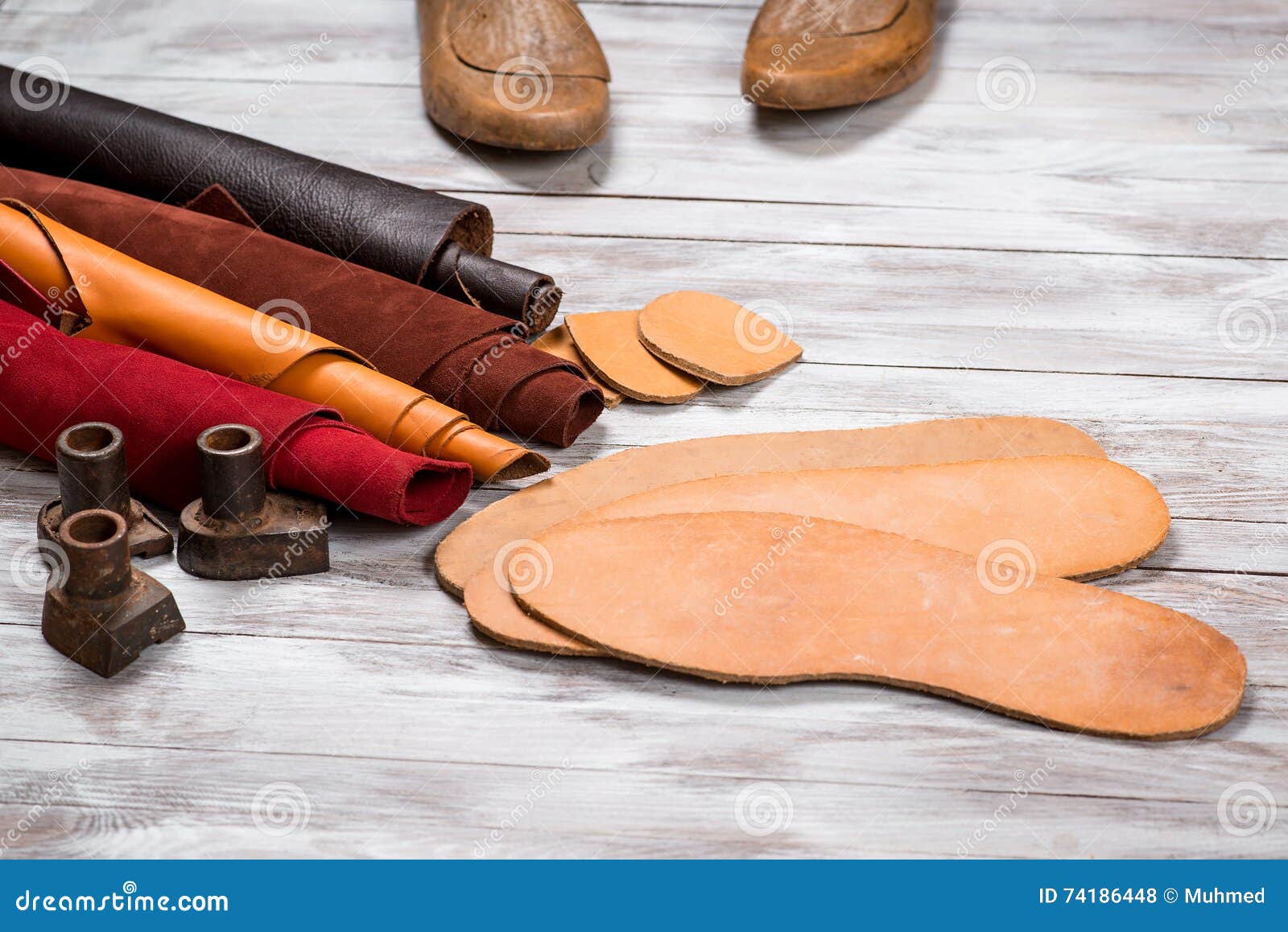 set of leather in rolls, craft tools on white wooden background. workplace for shoemaker. working handmade tools on a work table.