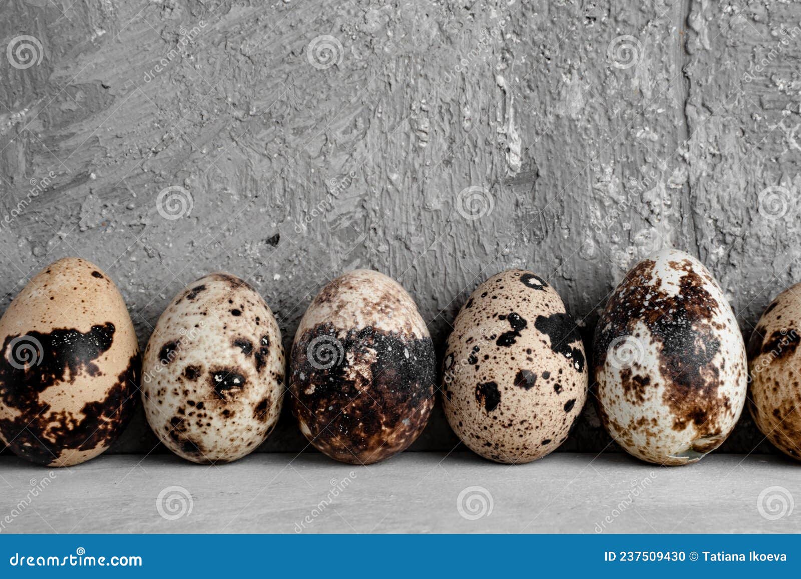 A Set of Small Beige Quail Eggs with Brown Spots are on a White