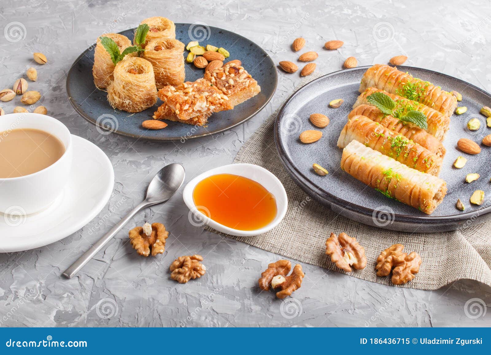 set of various traditional arabic sweets: baklava, kunafa, basbus in  ceramic plates on a gray concrete background. top view