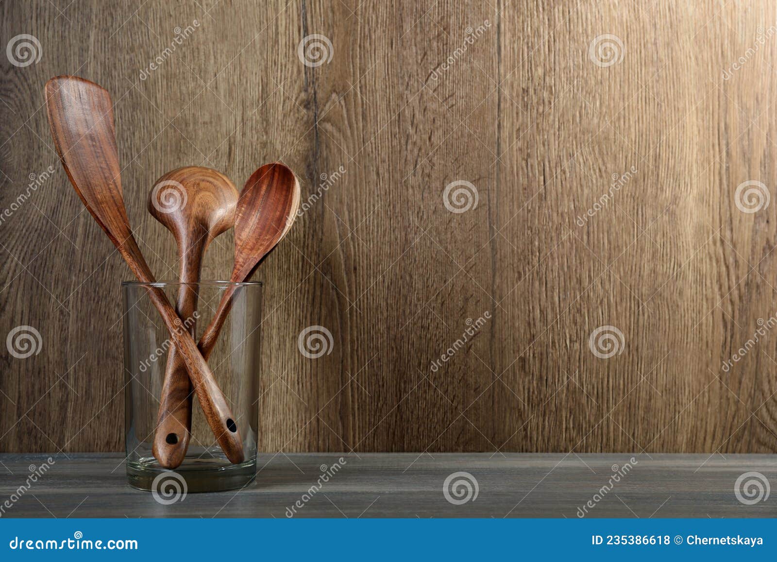 Set of Wooden Kitchen Utensils in Glass Holder on Grey Table. Space for