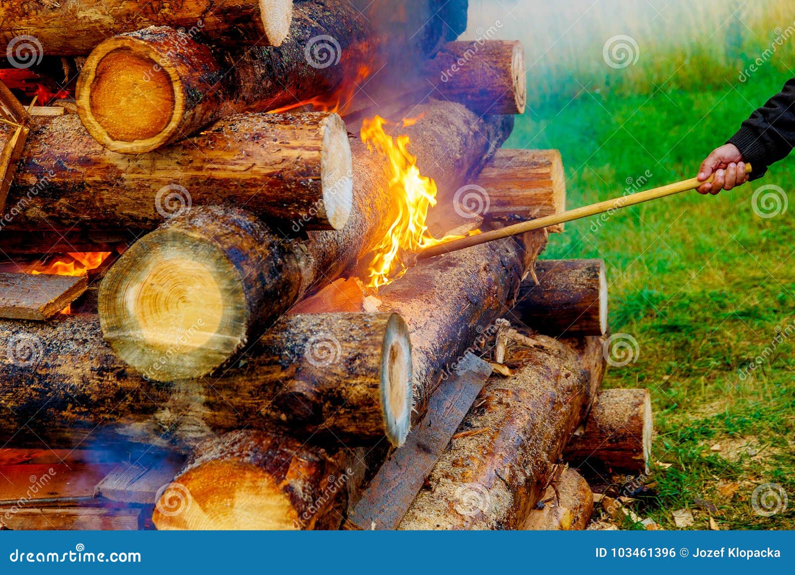 Setting Big Bonfire Made of Logs on Fire with Torch. Stock Photo