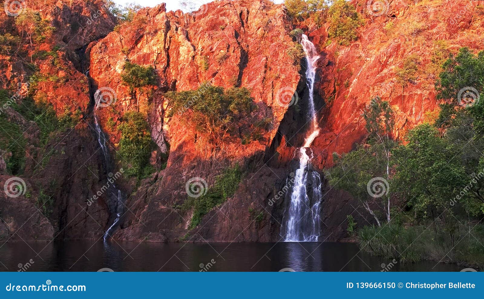 setting sun turns the cliffs at wangi waterfalls in litchfield national park a brilliant red