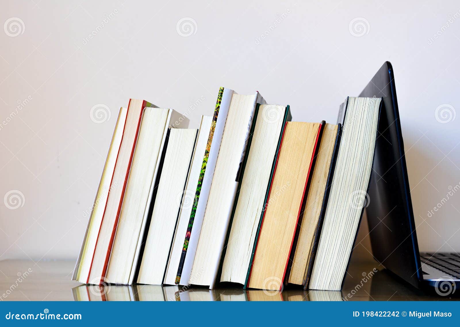 several books resting on a laptop, as if it were a bookend