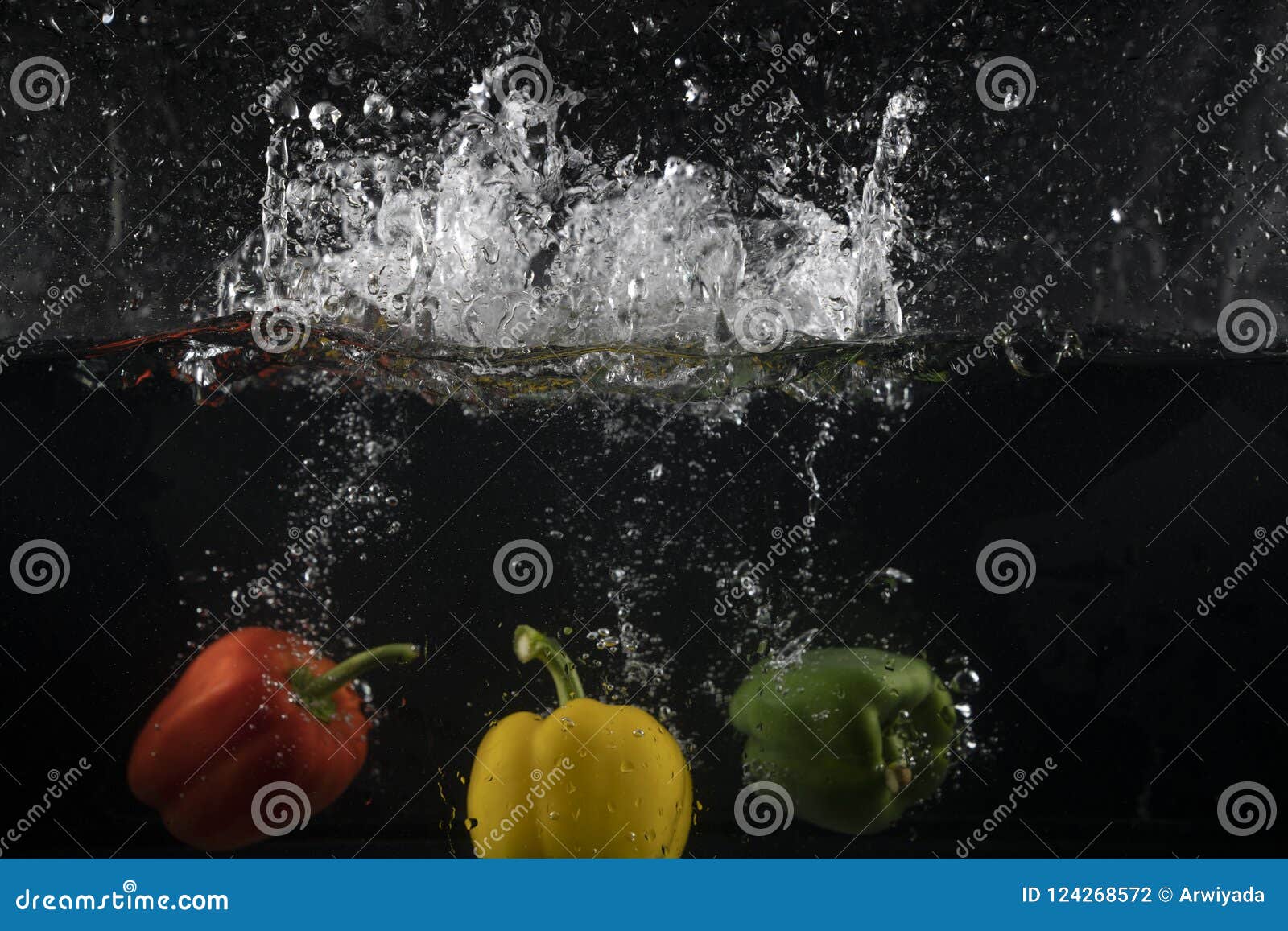Several Coloured Paprika Falling into Water Splash with Many Bub Stock