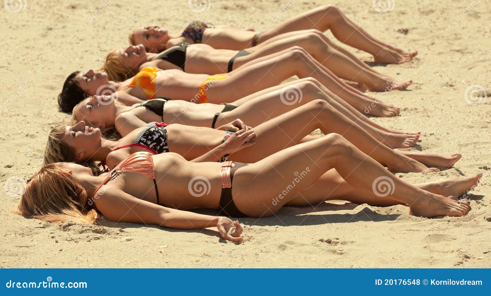 Several Girls in Bikini Lying on Sandy Beach Stock Photo