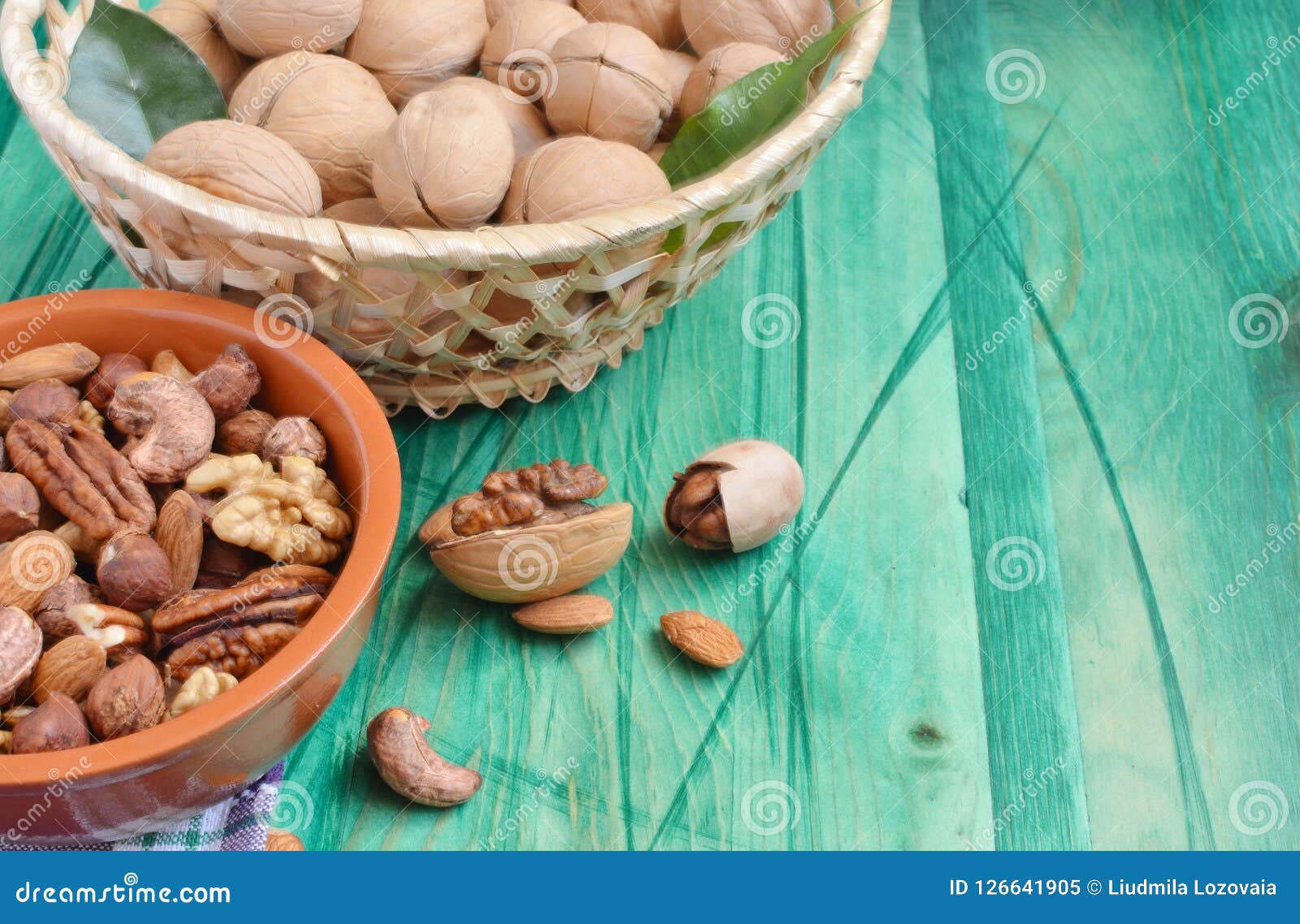 walnuts in a basket and nuts in a bowl on a green background of copi space