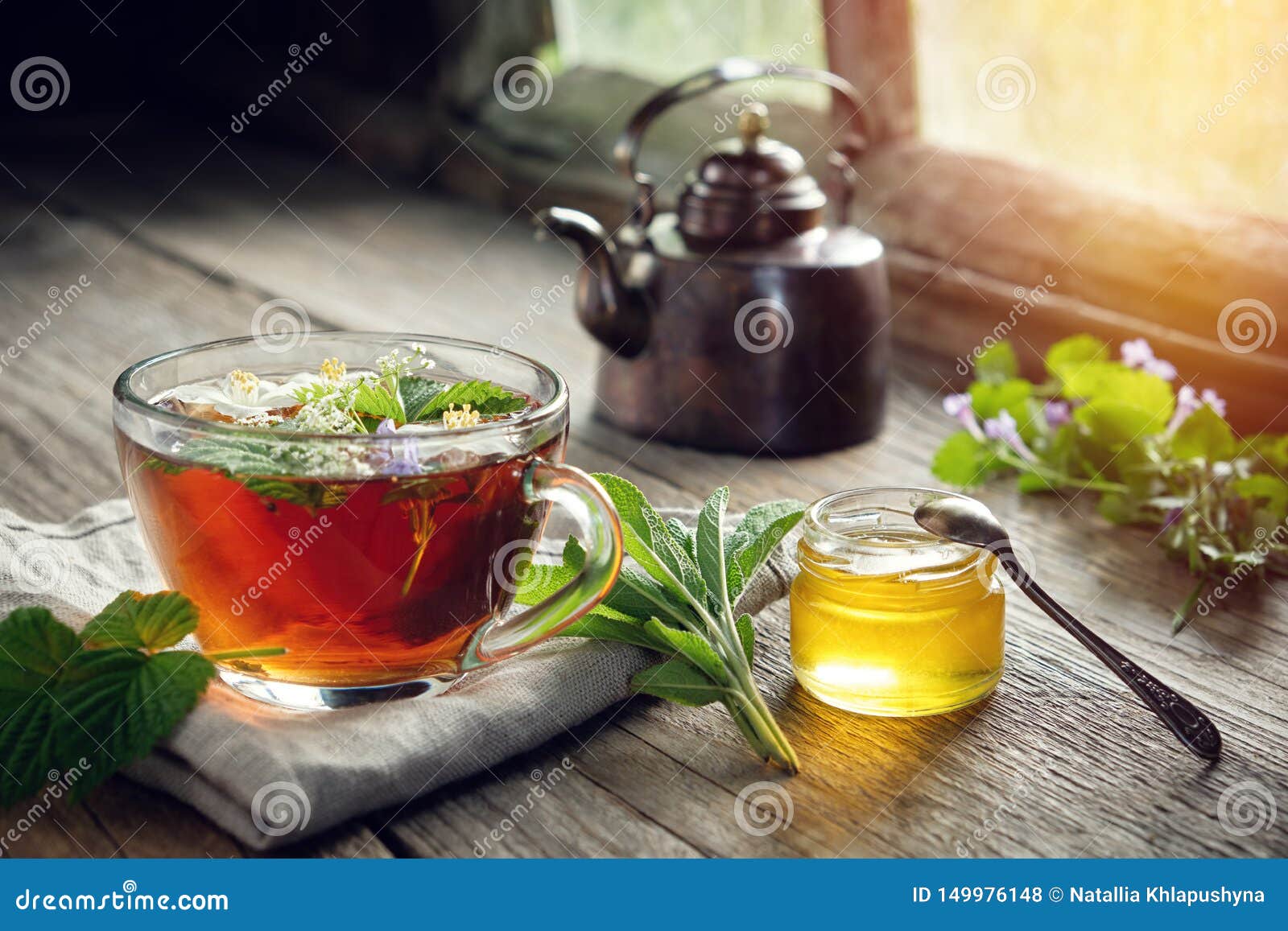 several medicinal plants and herbs on table, healthy herbal tea cup, honey jar and vintage copper tea kettle