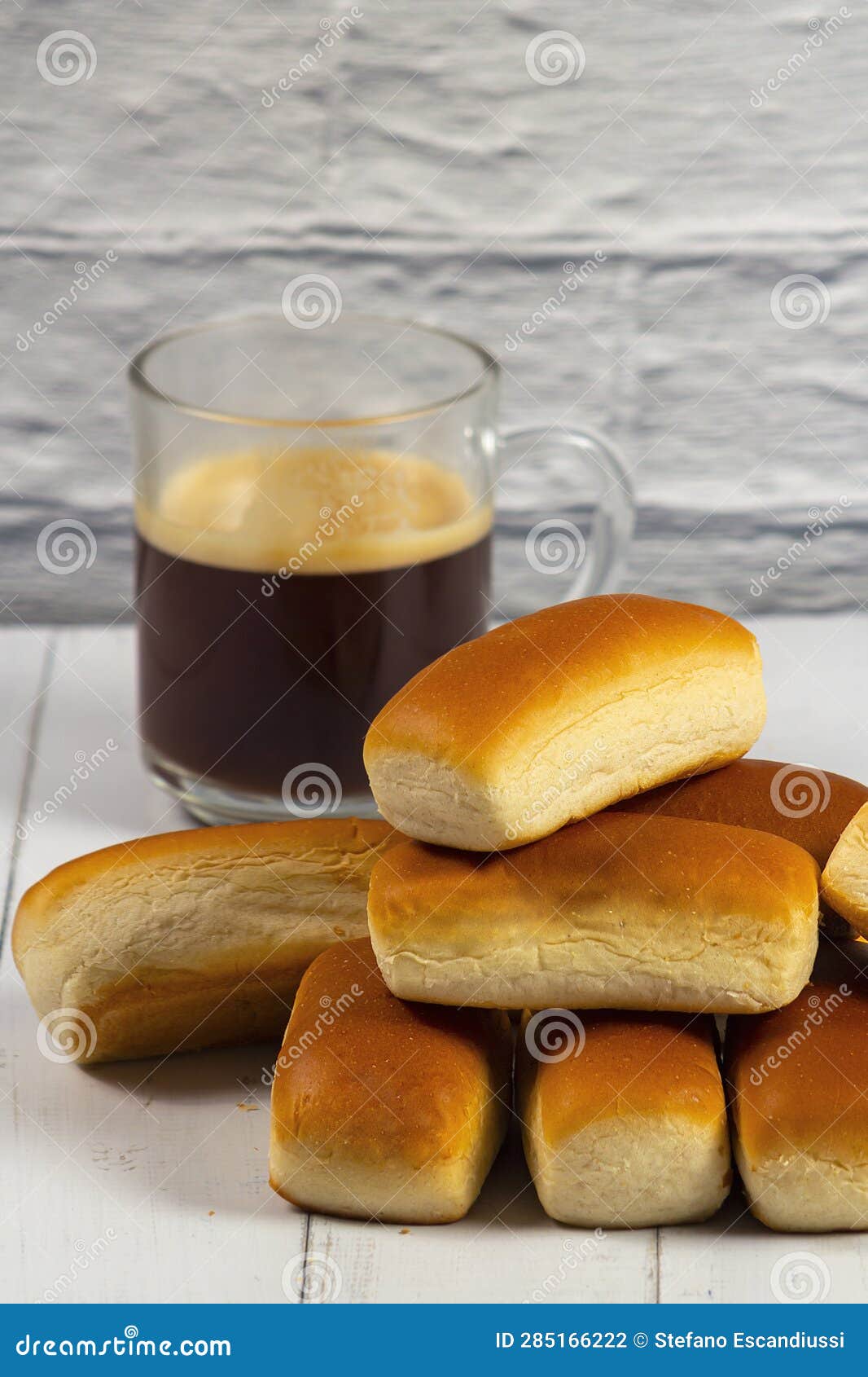 several mini buns and a mug of coffee on a white wooden table. selective focus