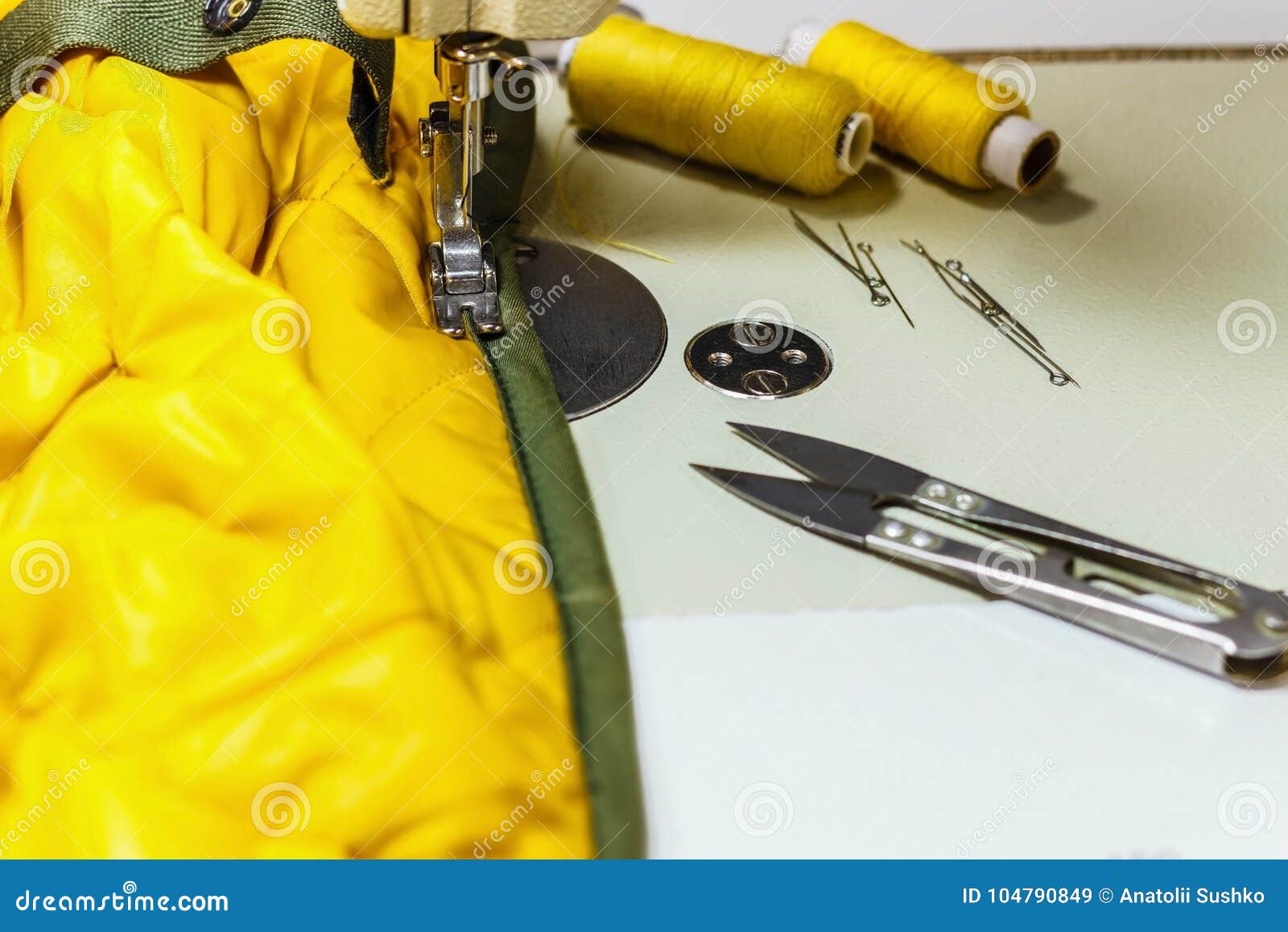On the Sewing Machine is a Yellow Jacket, Threads and Scissors. Stock